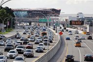 In this Aug. 1, 2018, photo, cars on the Grand Central Parkway pass LaGuardia Airport in New York. The Trump administration has proposed rolling back tougher Obama-era gas mileage requirements that are set to take effect after 2020.